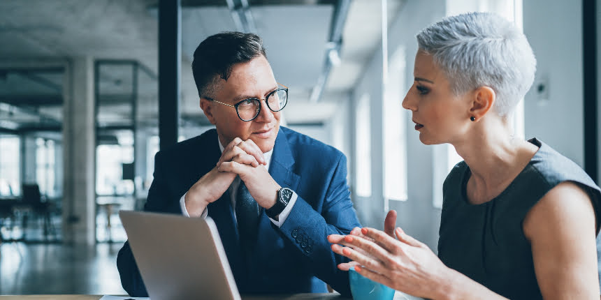 E-leadership: homem e mulher conversando no trabalho olhando para um computador