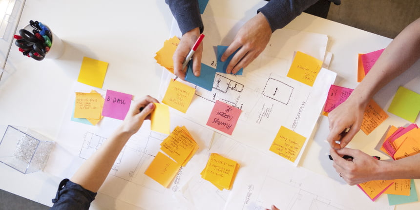 Job to Be Done: quadro com vários post-its e três colegas trabalhando nele